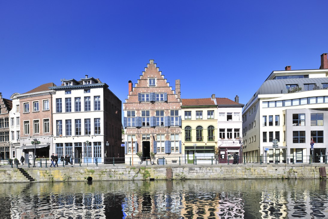 Historic Flemish buildings with stepped gable roofs line the Kraanlei waterfront in Ghent, Belgium.