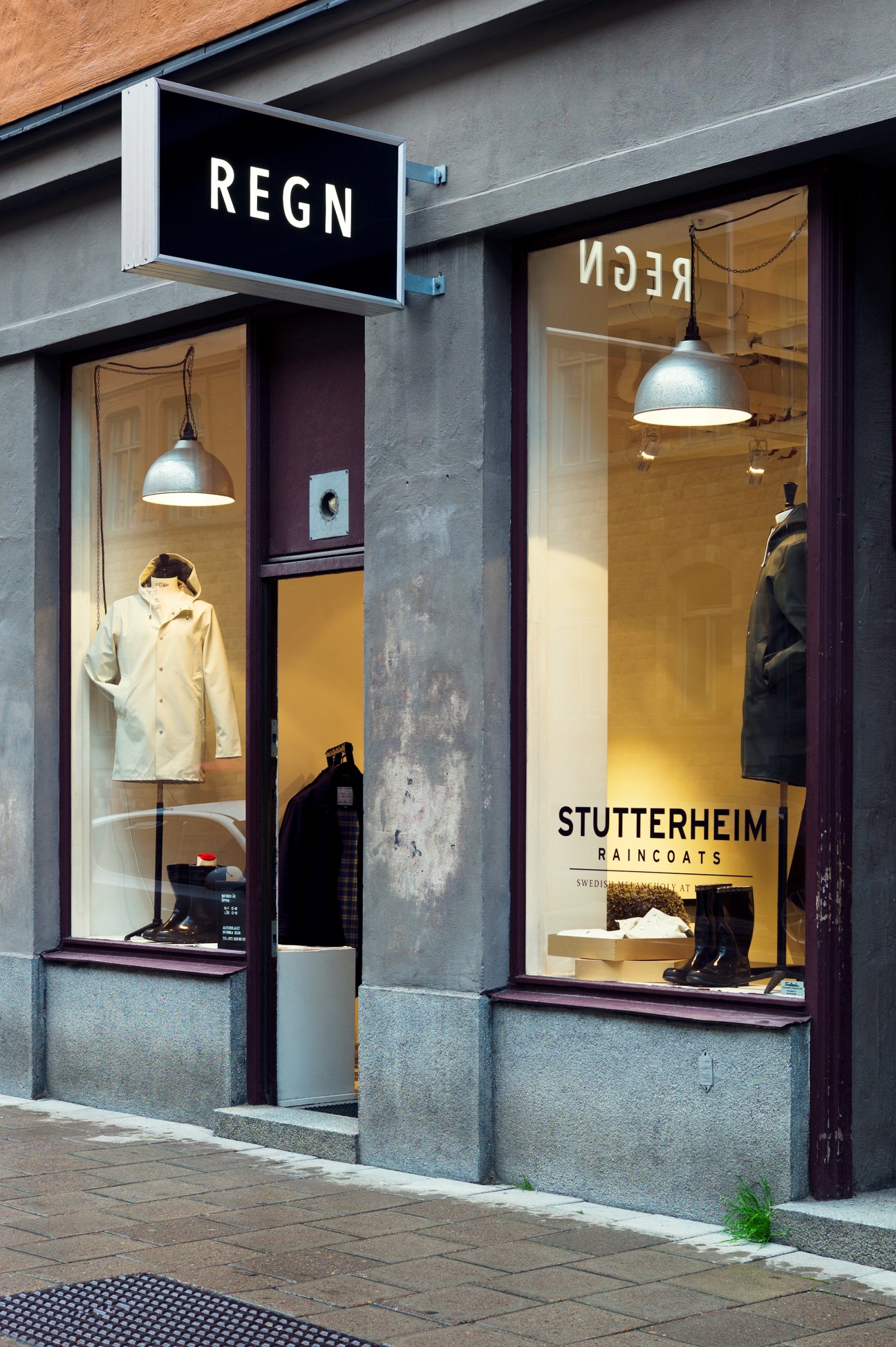 Stutterheim raincoat shop storefront in Stockholm with yellow and black raincoats displayed in windows.