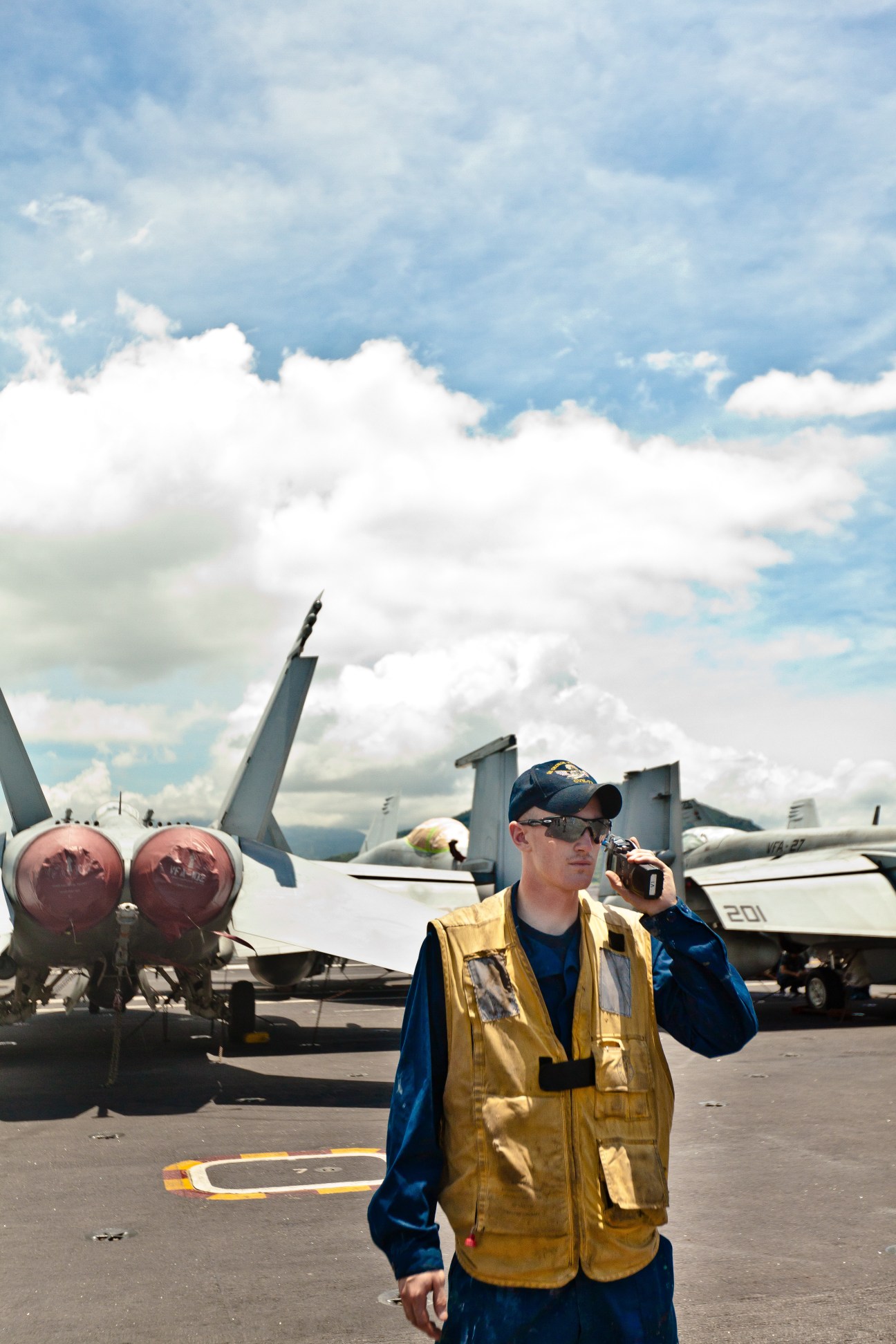 A crew member in a yellow safety vest directs aircraft on the USS George Washington flight deck.