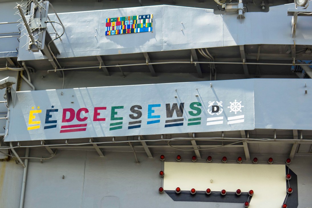 Colorful naval signal flags and emblems displayed on the USS George Washington carrier hull.
