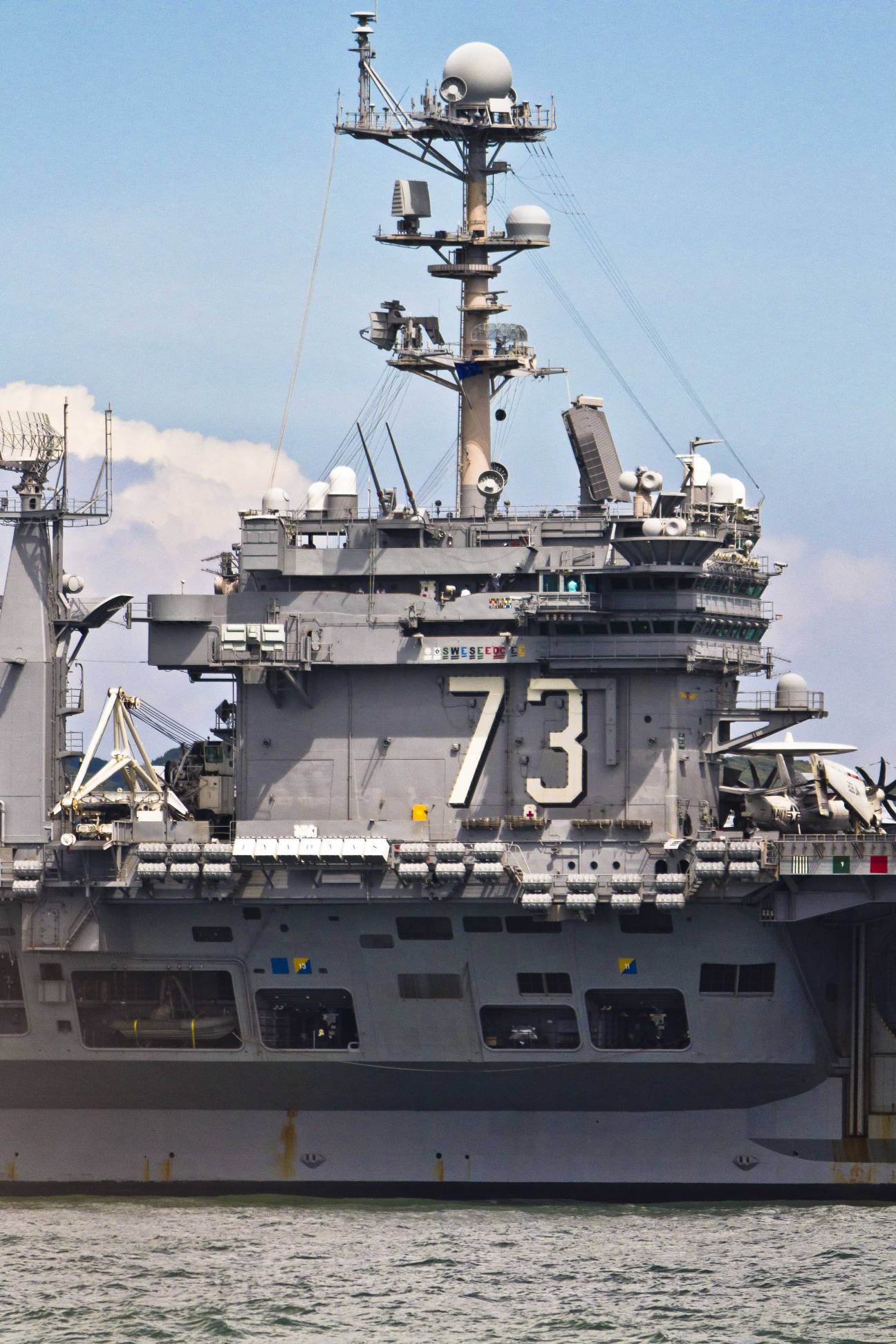 USS George Washington aircraft carrier superstructure showing hull number 73, radar equipment, and navigation tower against sky.