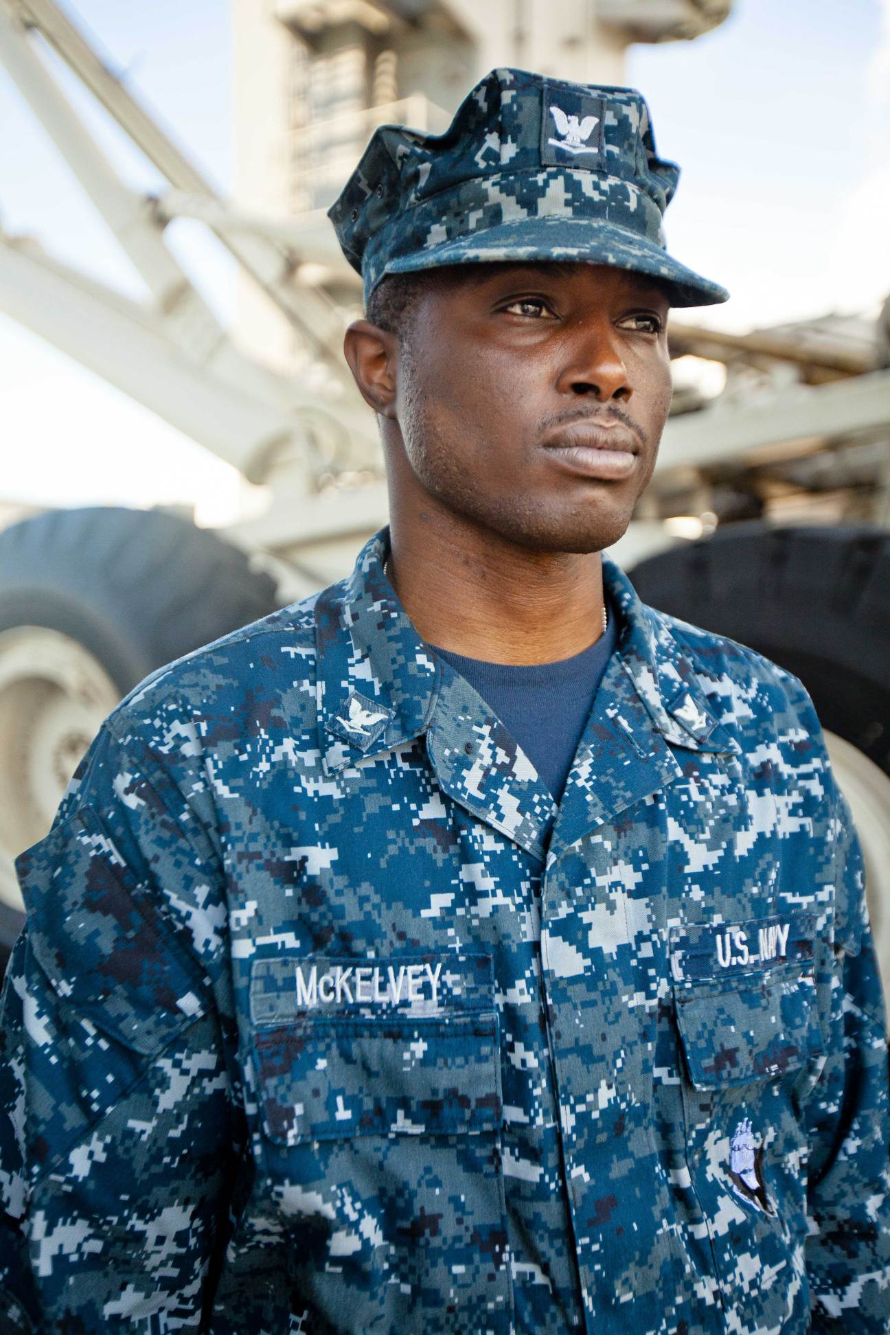 US Navy sailor in digital camouflage uniform and cap stands on USS George Washington flight deck.