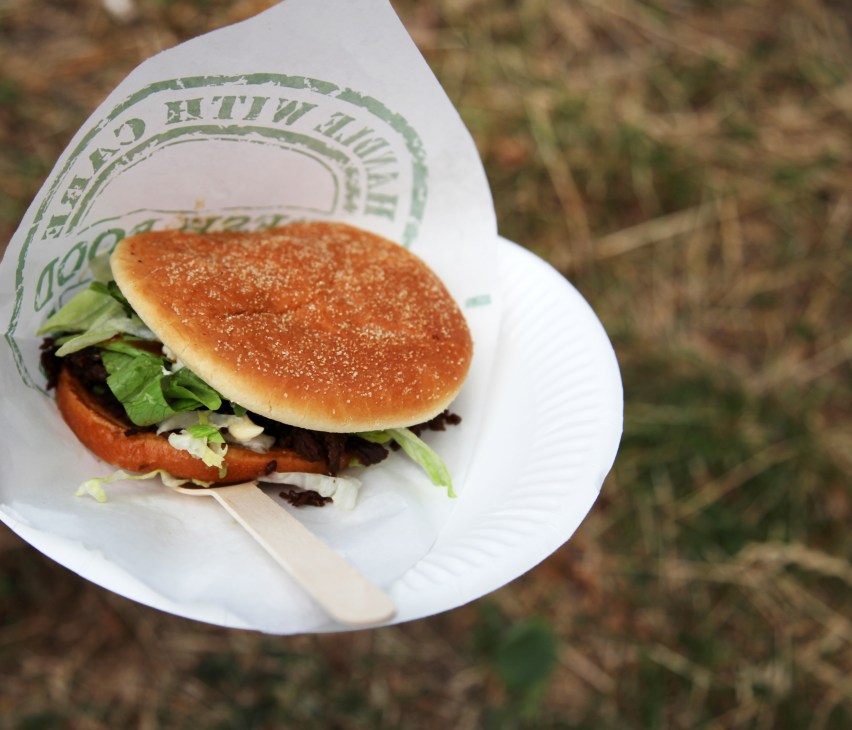 A gourmet burger with sesame seed bun, lettuce and meat on a white paper wrapper from a Stockholm food truck.