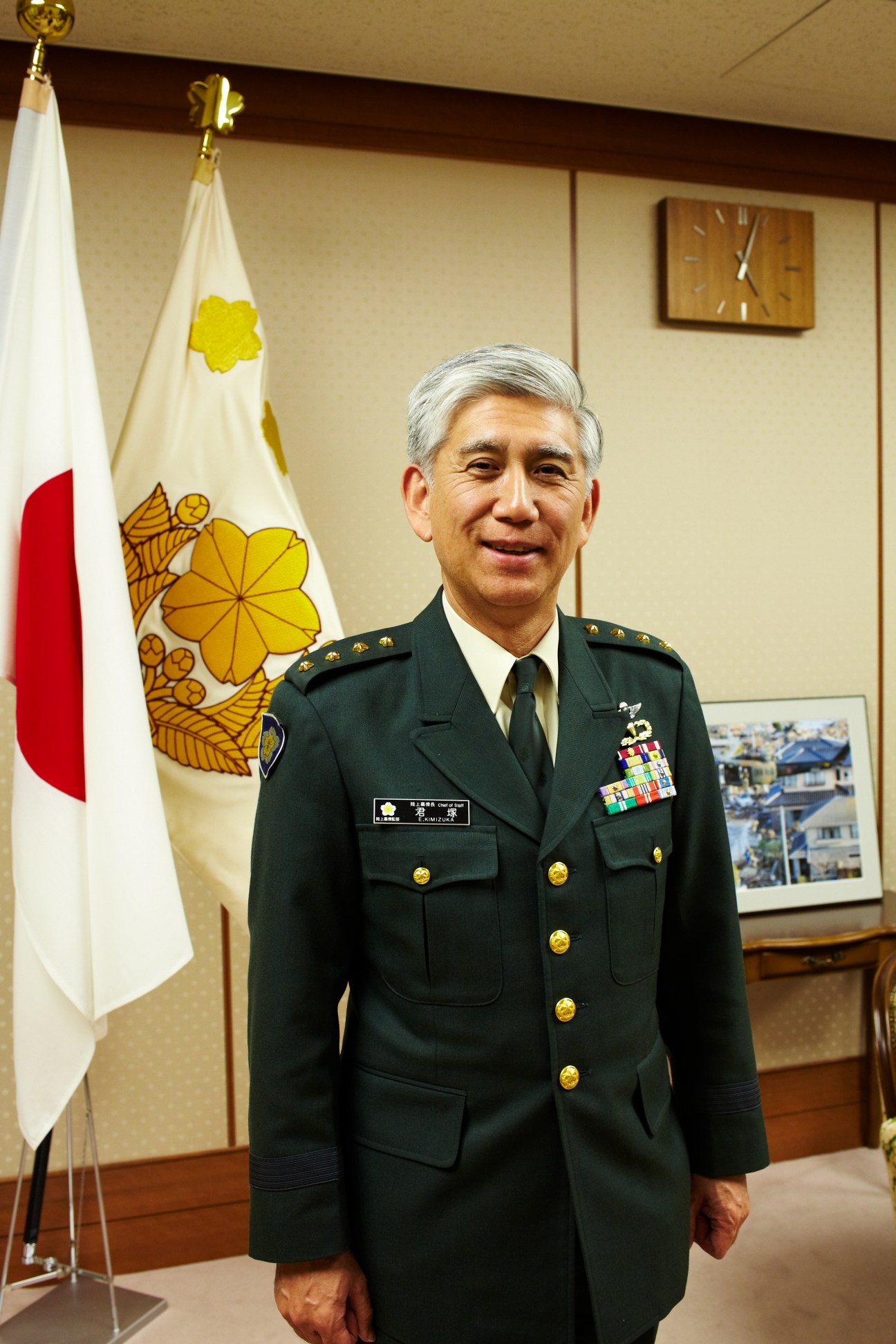 General Eiji Kimizuka in dress uniform standing before the Japanese national flag and GSDF insignia in his Tokyo office.