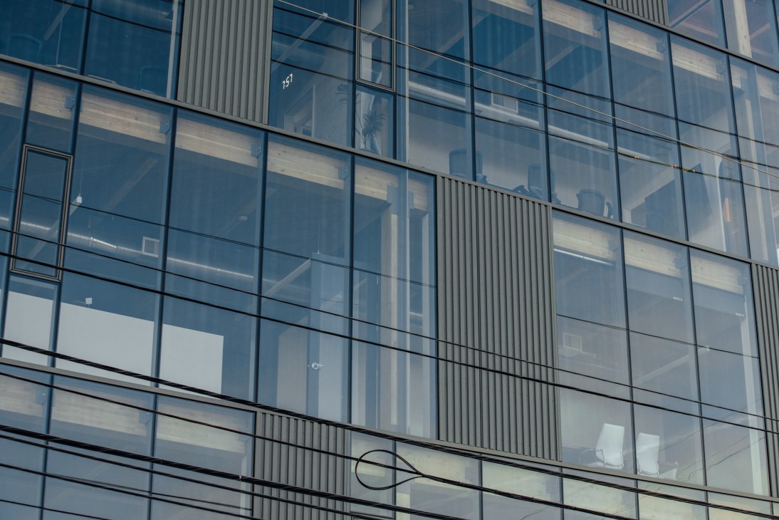 Modern glass building facade with geometric window grid and vertical metal sun shades