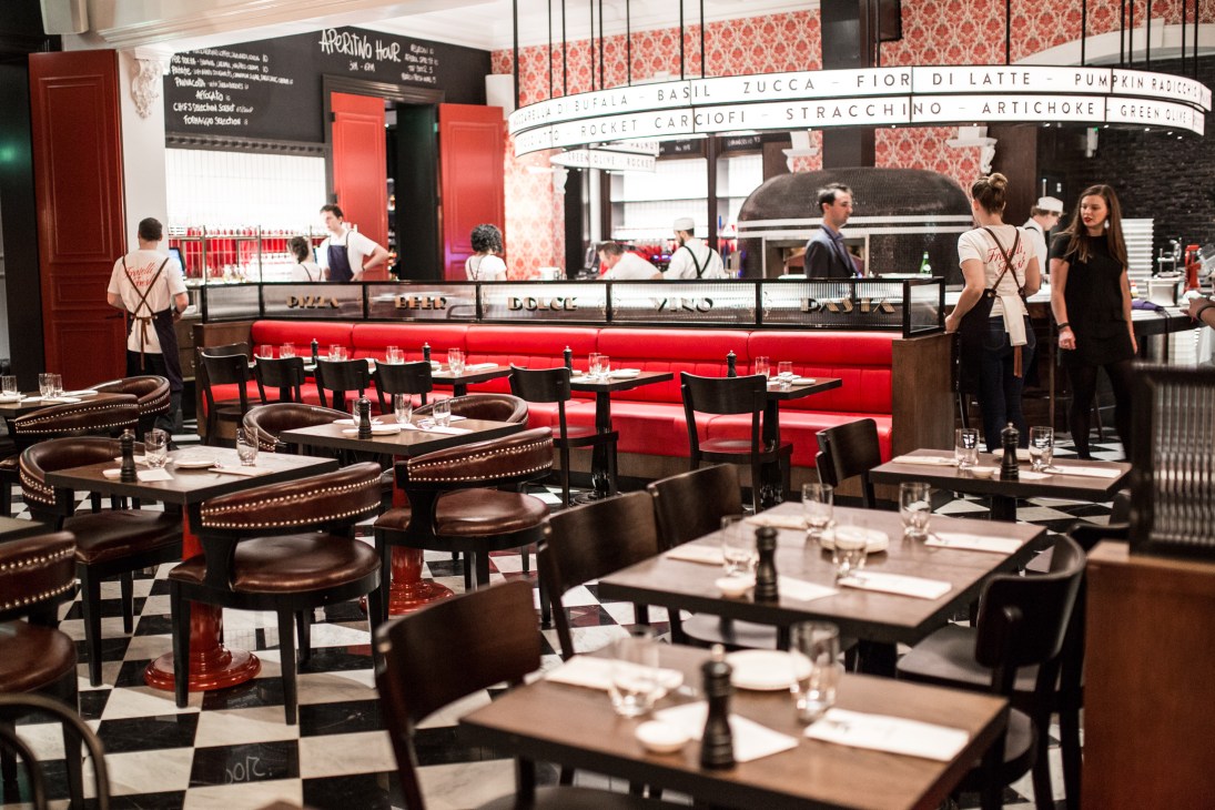 Fratelli Fresh restaurant interior with red velvet banquette, black chairs, checkered floor and open kitchen counter.