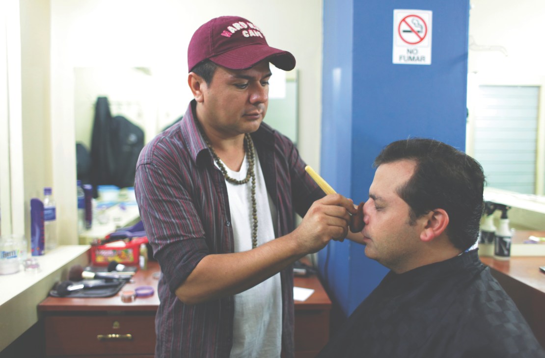 Makeup artist Eduardo Quintanilla applies makeup to Carlos Dada in a dressing room before a TV appearance.