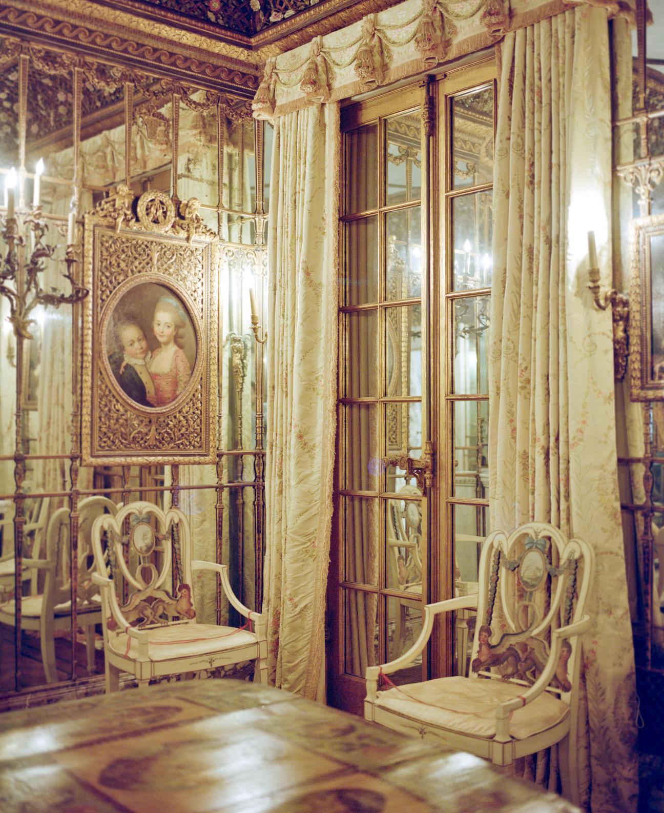 Ornate Venetian room with cream and gold paneling, period furniture, and classical portrait painting.