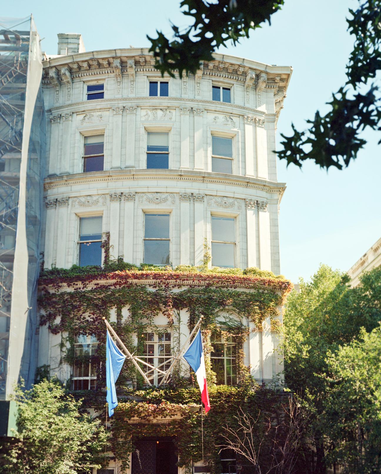 Ivy-covered neoclassical townhouse with French and EU flags on Upper East Side Manhattan.