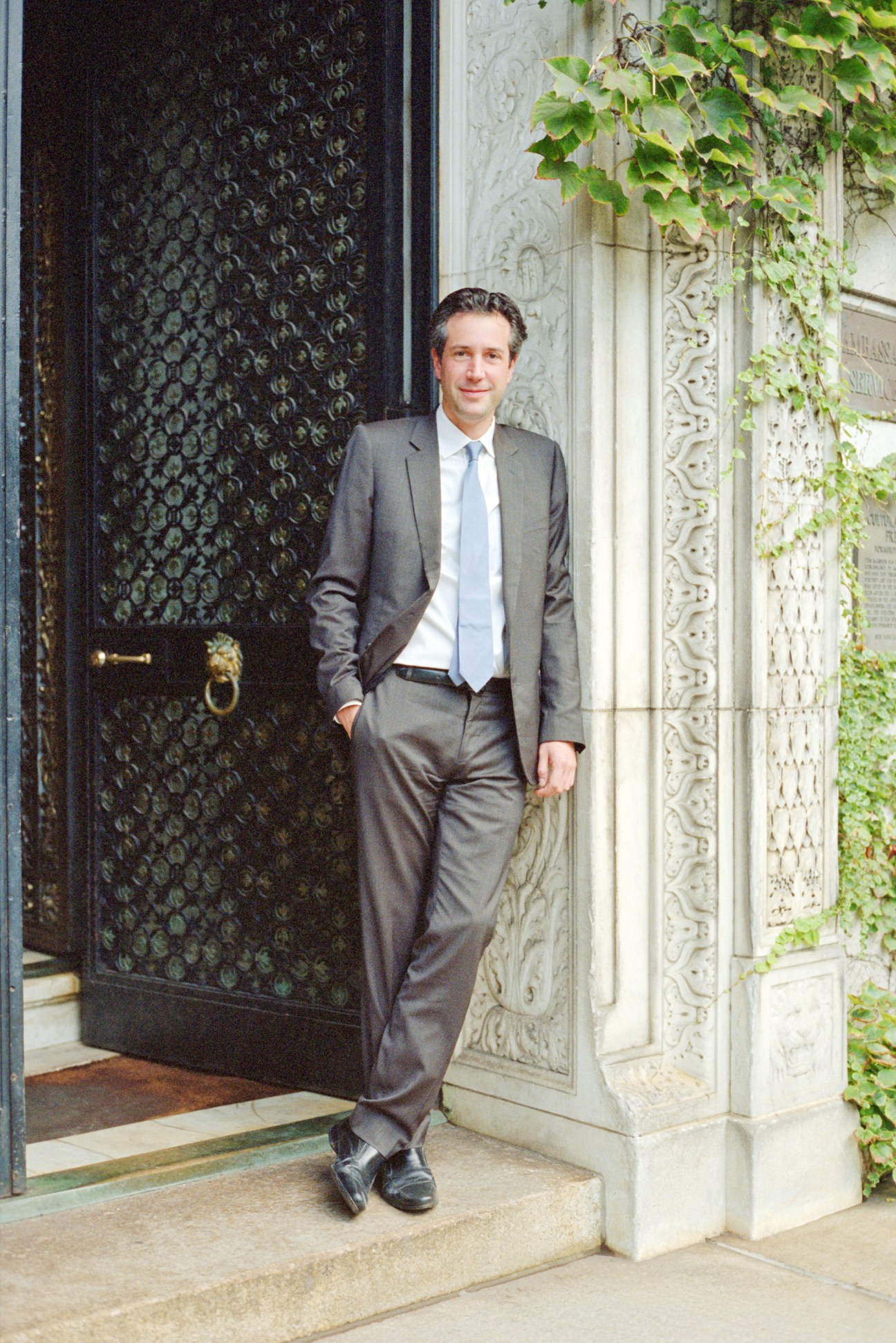 Antonin Baudry stands in a grey suit outside the French Embassy entrance in New York.