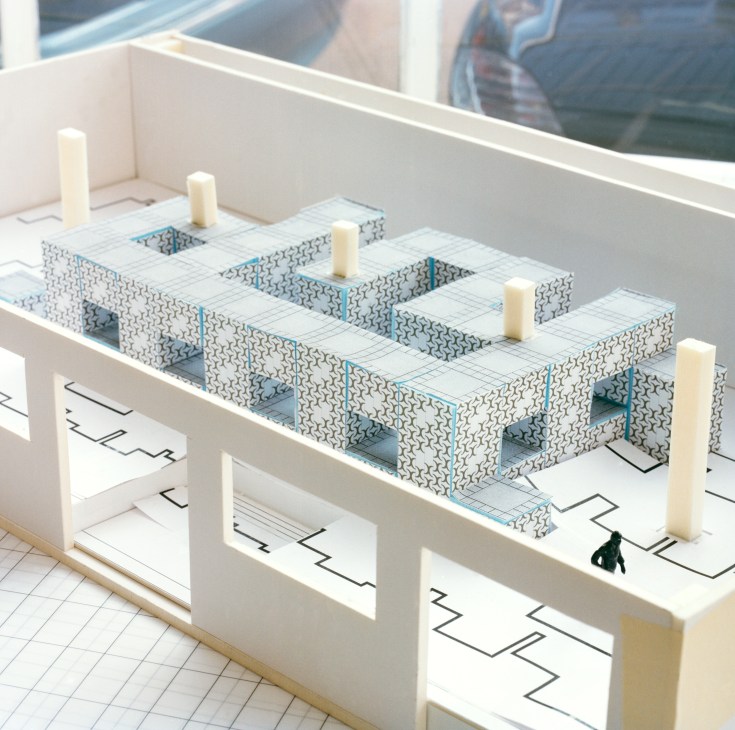 Architectural model of Nebula art installation showing patterned blocks with blue accents and cream pillars on a gridded base.