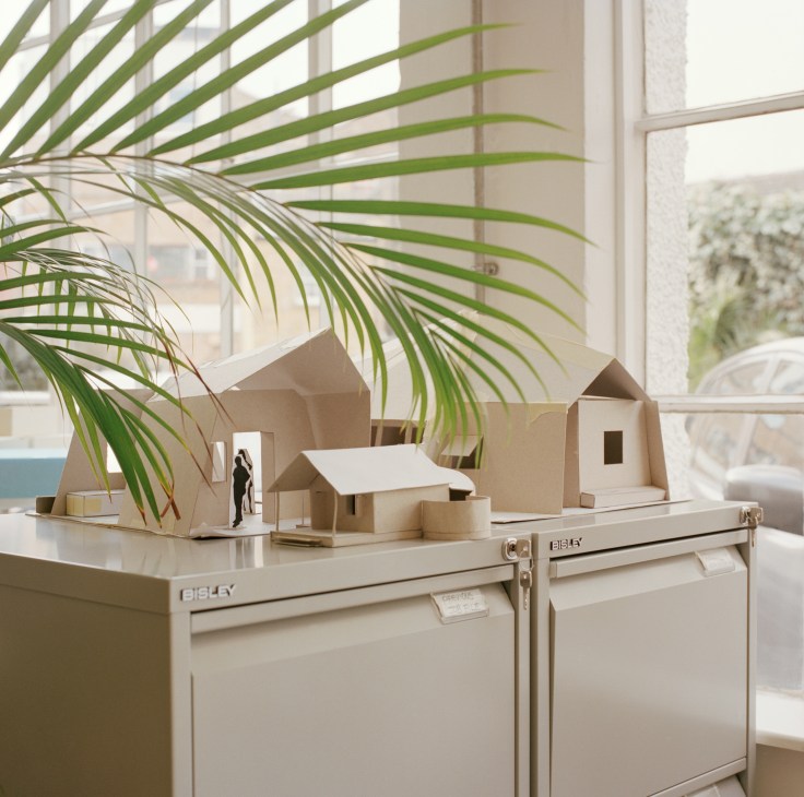 Architectural model of Palagama Sri Lankan resort displayed on filing cabinets with palm fronds overhead.