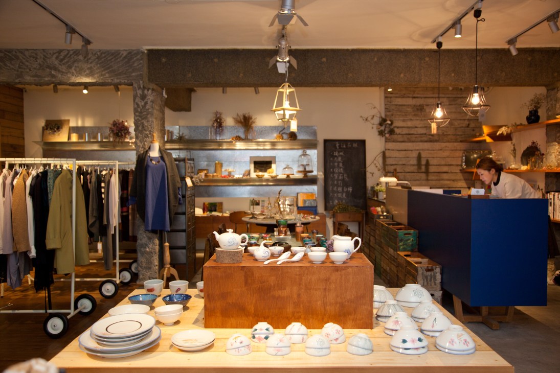 Interior of Sense30 shop displaying ceramics, tableware, and clothing with industrial ceiling and pendant lighting.