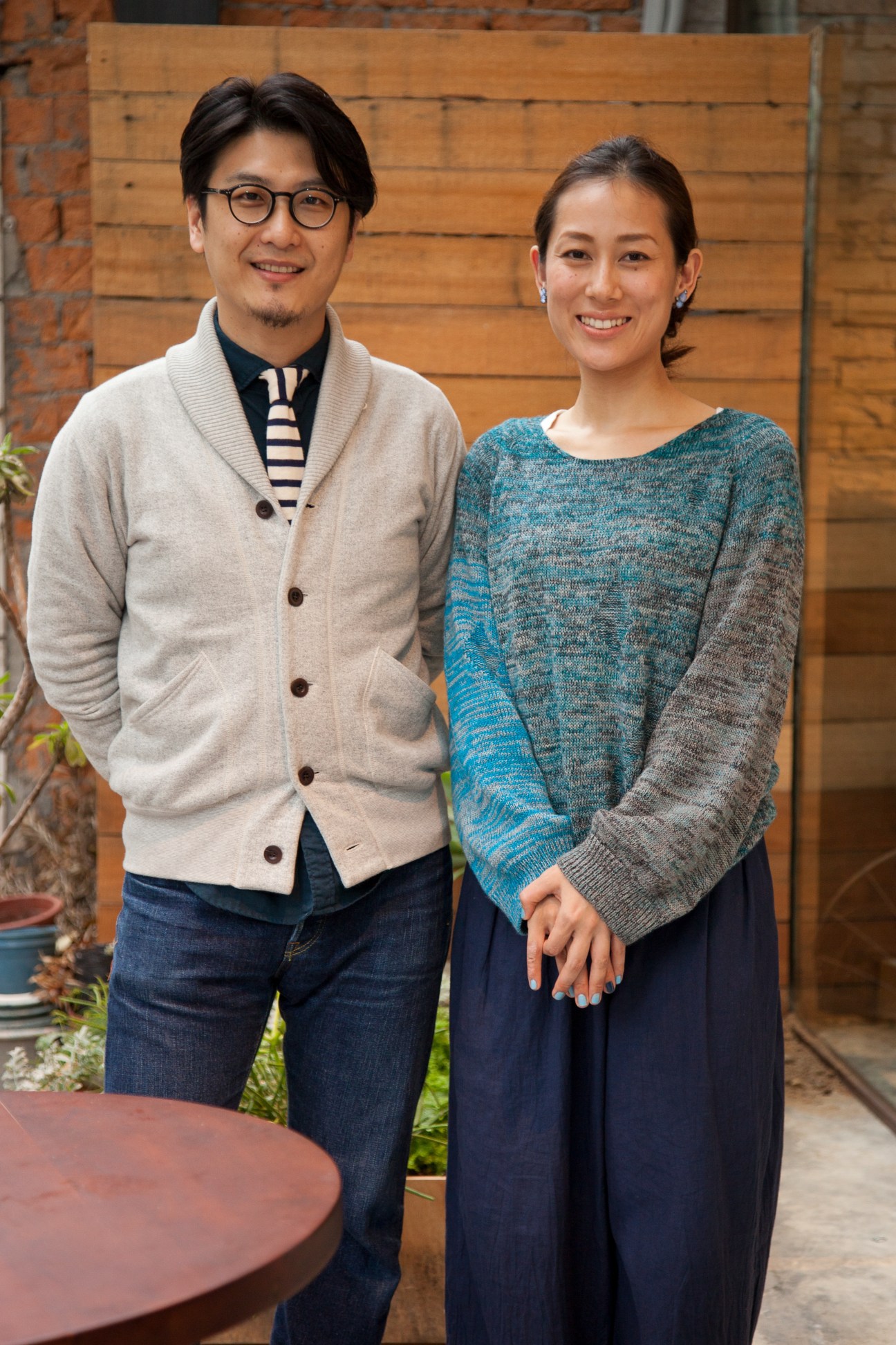 Jay Wu and Midori Mukohara, founders of Fujin Tree 355, pose together in front of a wooden wall.