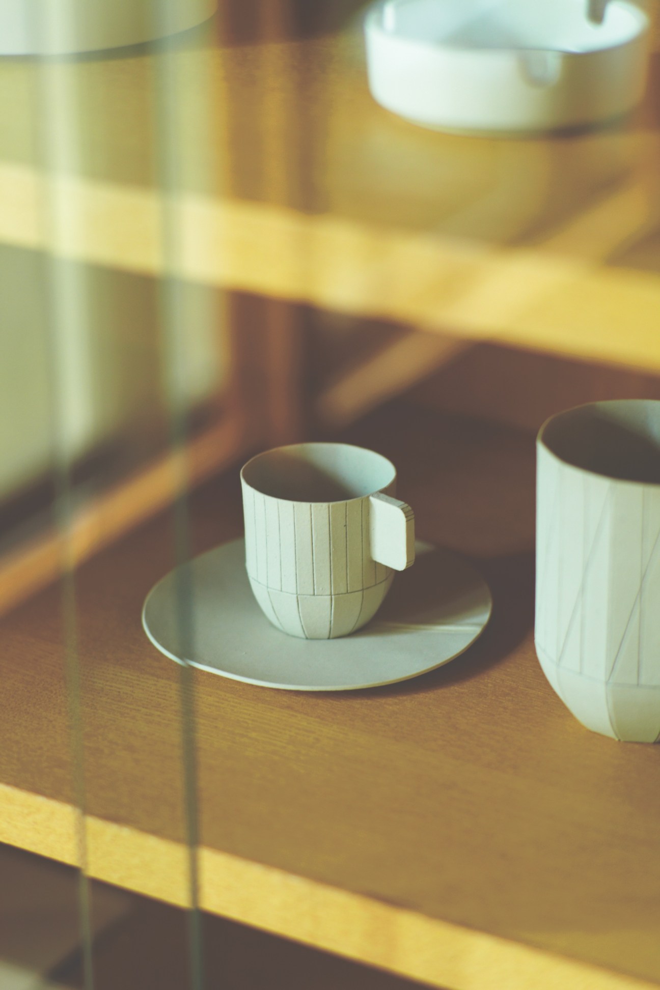 White ceramic cup with vertical line pattern on saucer in sunlit interior