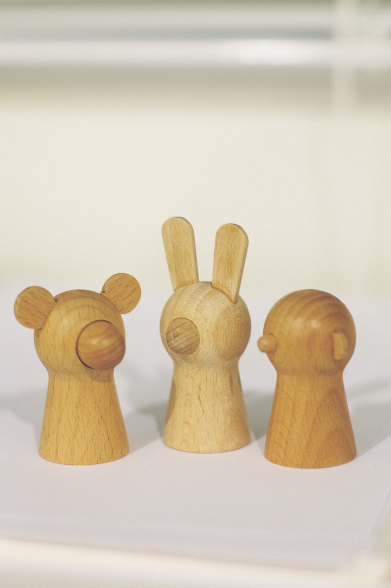 Three wooden finger puppets with simple carved features and natural wood finish.