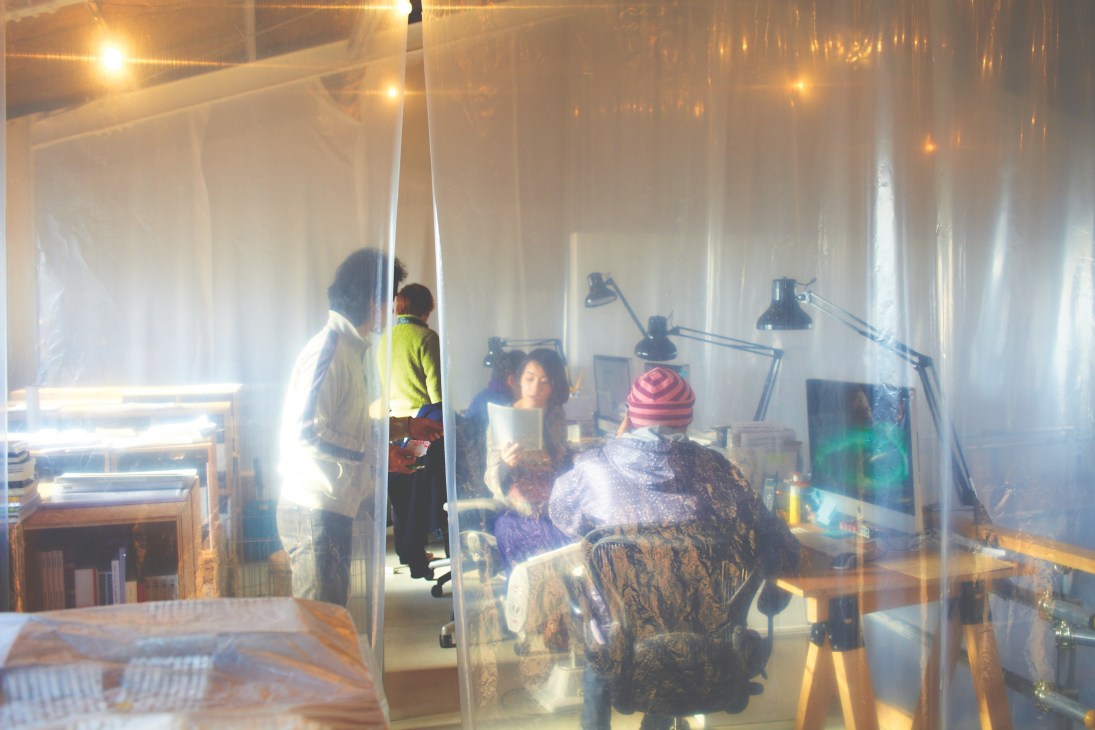 Group of creatives working together in a bright studio space with pendant lights and white walls.