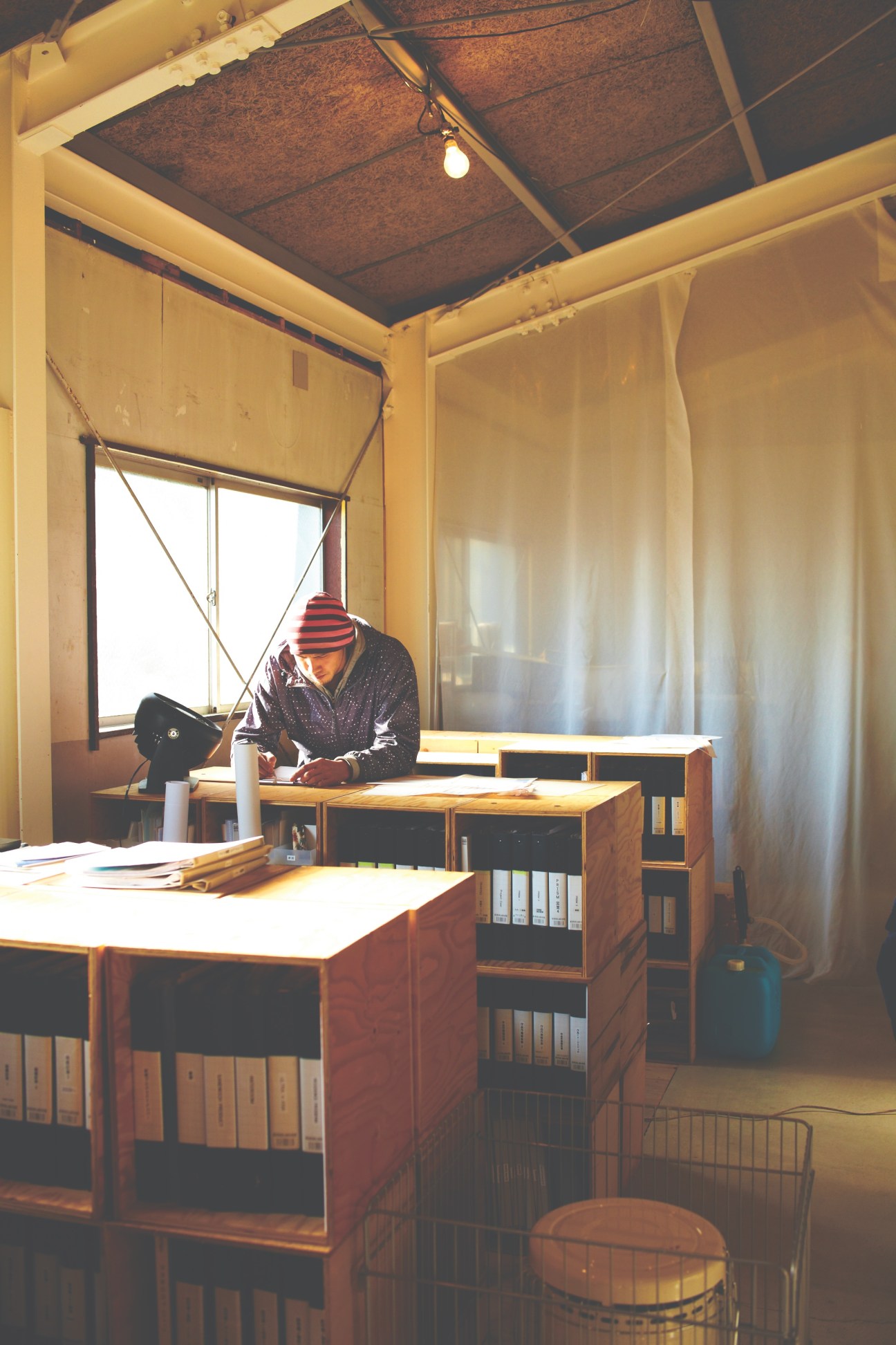 Designer working at desk in converted sandwich factory studio with yellow walls and industrial ceiling.