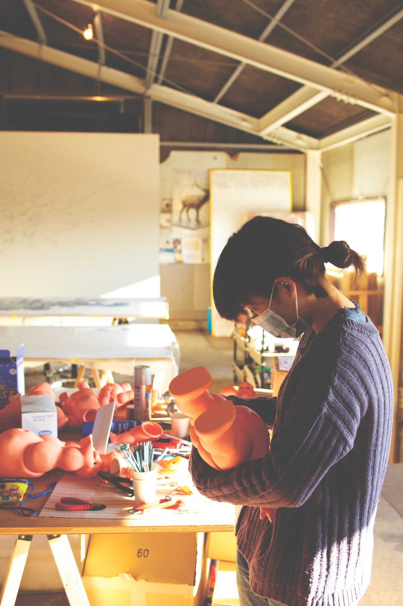 Designer working on red plastic components at a wooden table in a bright studio workshop.