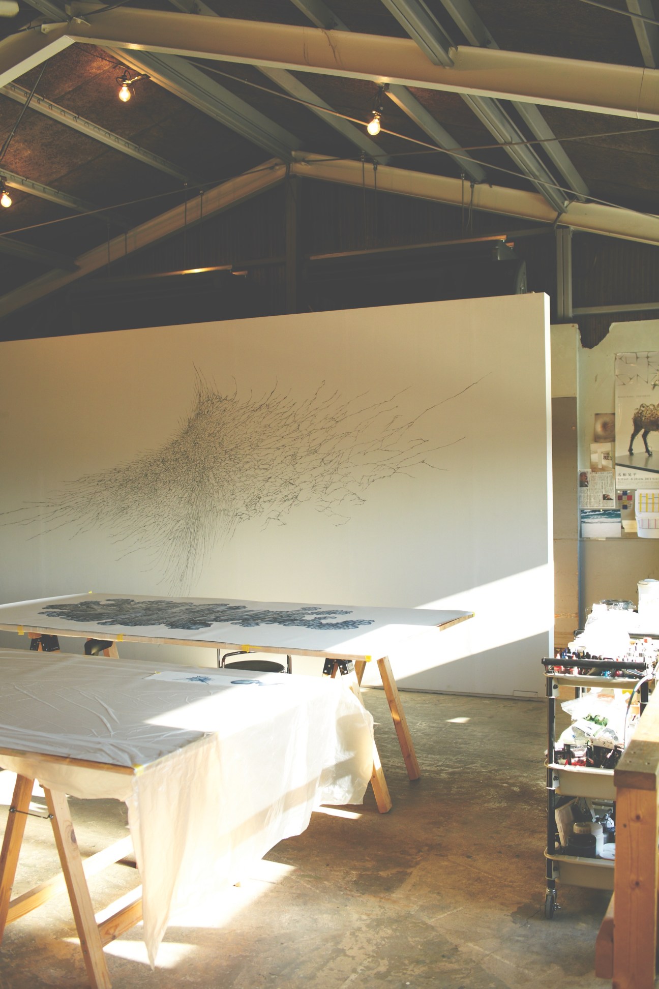 Large-scale artwork with intricate line drawings displayed in Kohei Nawa's converted factory studio workspace.