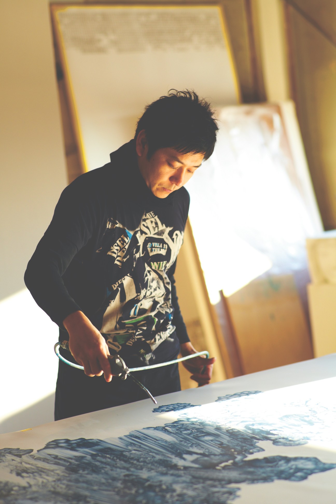 Kohei Nawa works on design projects at a table in his studio space.