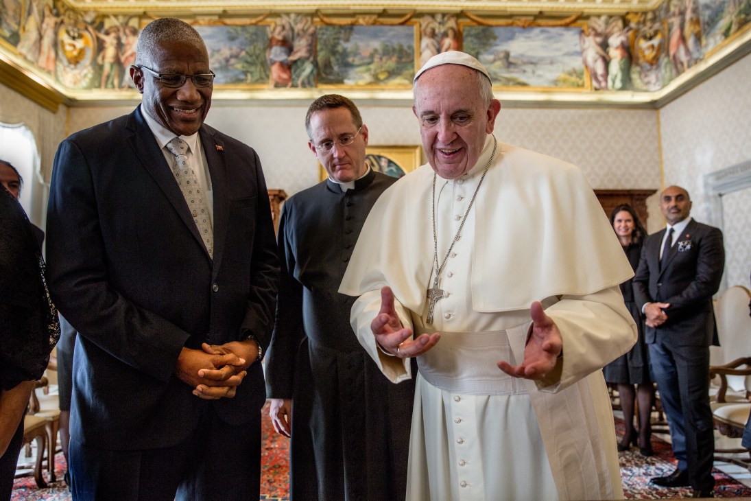 Pope Francis in white robes speaks with Sir Rodney Williams, governor-general of Antigua and Barbuda, in an ornate Vatican reception room.