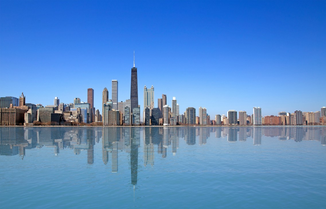 Chicago skyline reflected in Lake Michigan under a clear blue sky