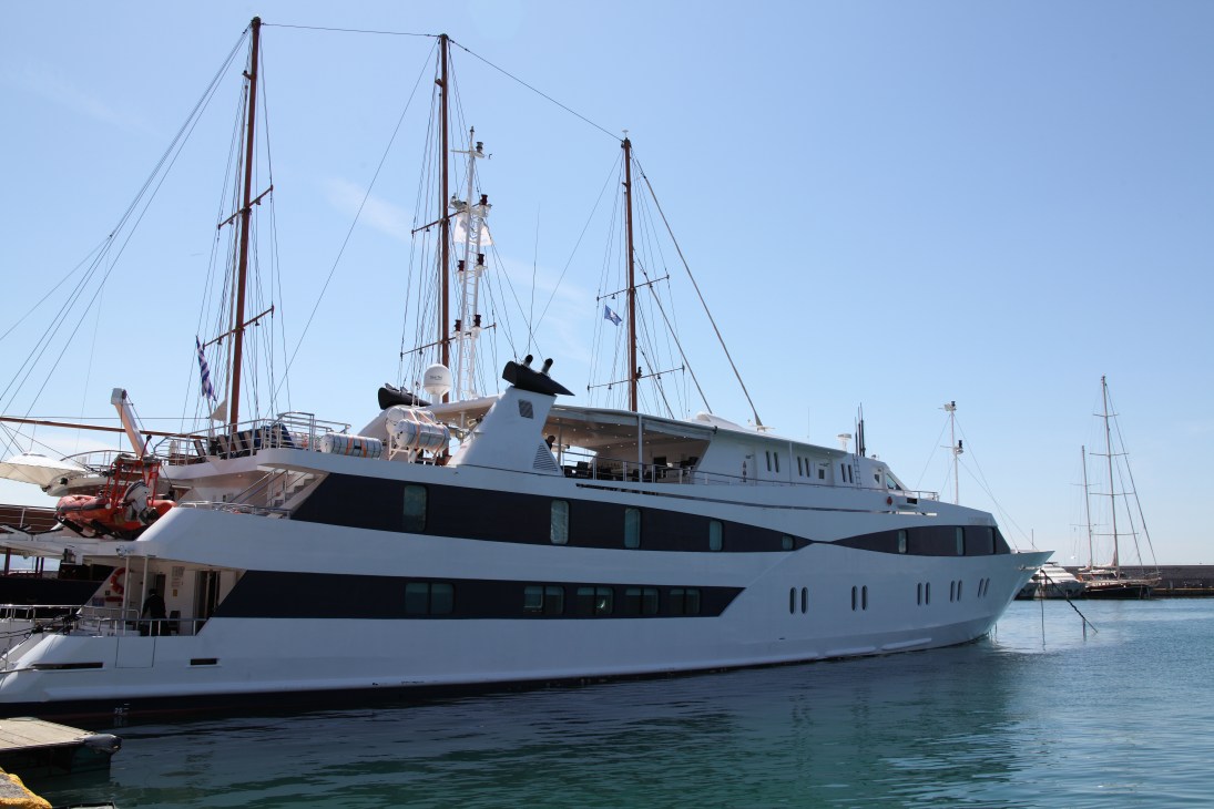 Small luxury yacht moored in harbour with tall masts and white hull