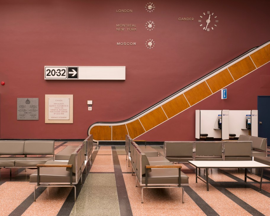 Gander International Airport's mid-century terminal lounge with wooden escalator, world clocks, mauve walls and period seating.