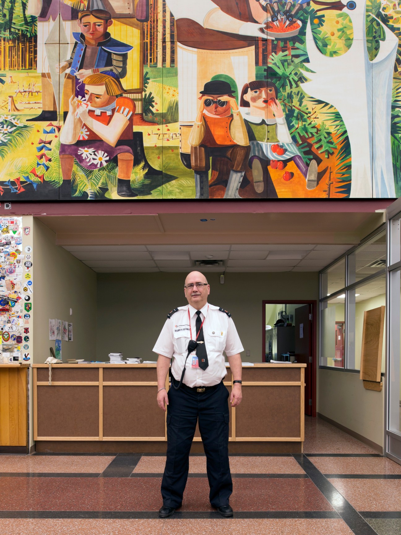Jerry Cramm, chief commissionaire at Gander International Airport, stands in uniform before a colorful mural.