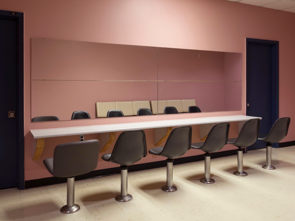 Gander International Airport's mirrored powder room with pink walls, white counter, and black Eames chairs.