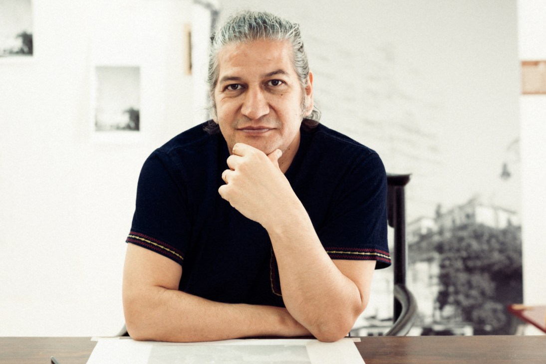 Portrait of Cuban artist Carlos Garaicoa in his Havana studio, resting his chin on his hand
