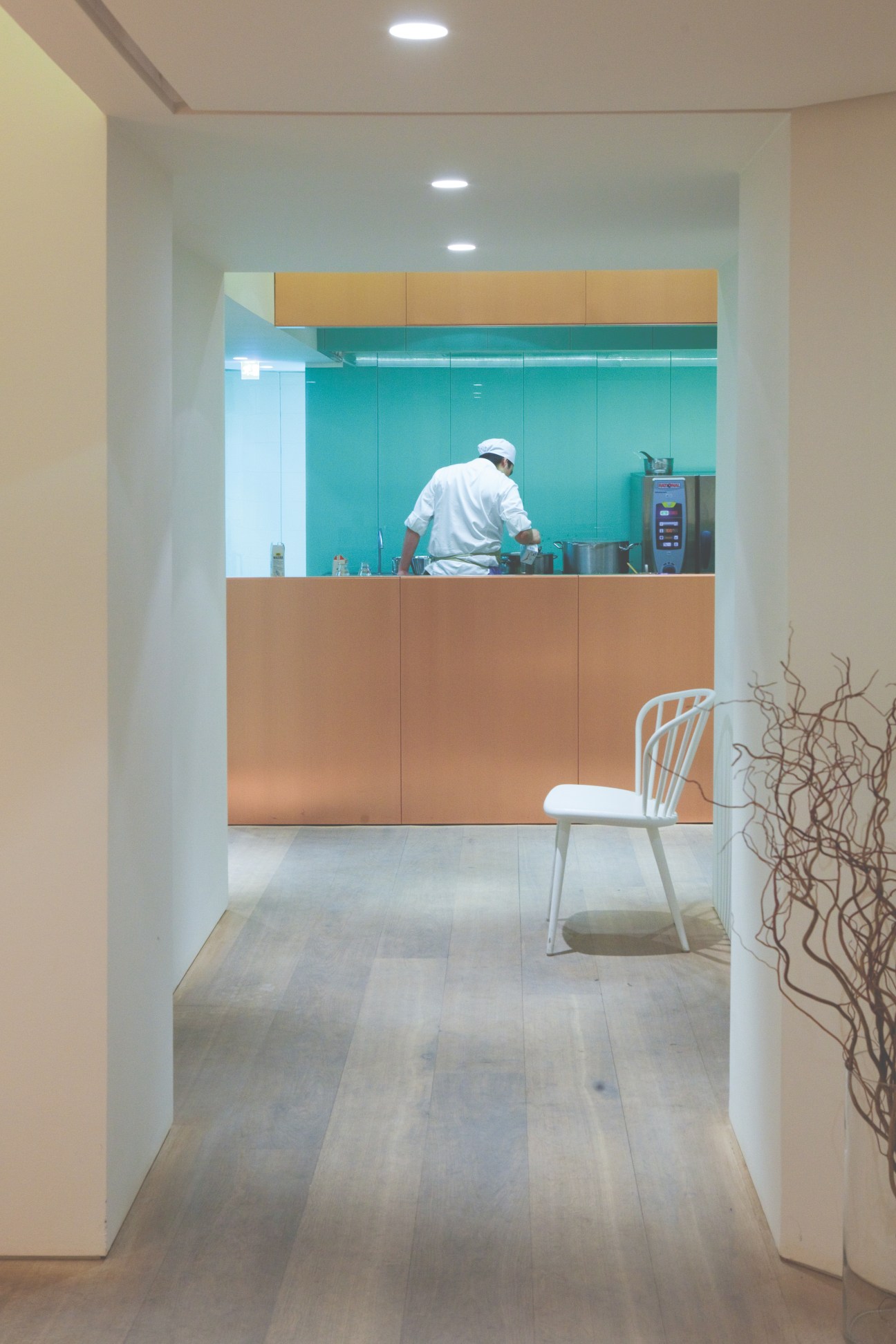 Chef working in open kitchen at Gastrologik restaurant with turquoise and wood-paneled design.