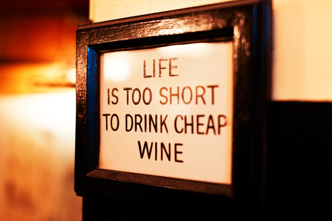 Framed sign reading 'Life is too short to drink cheap wine' on a restaurant wall.