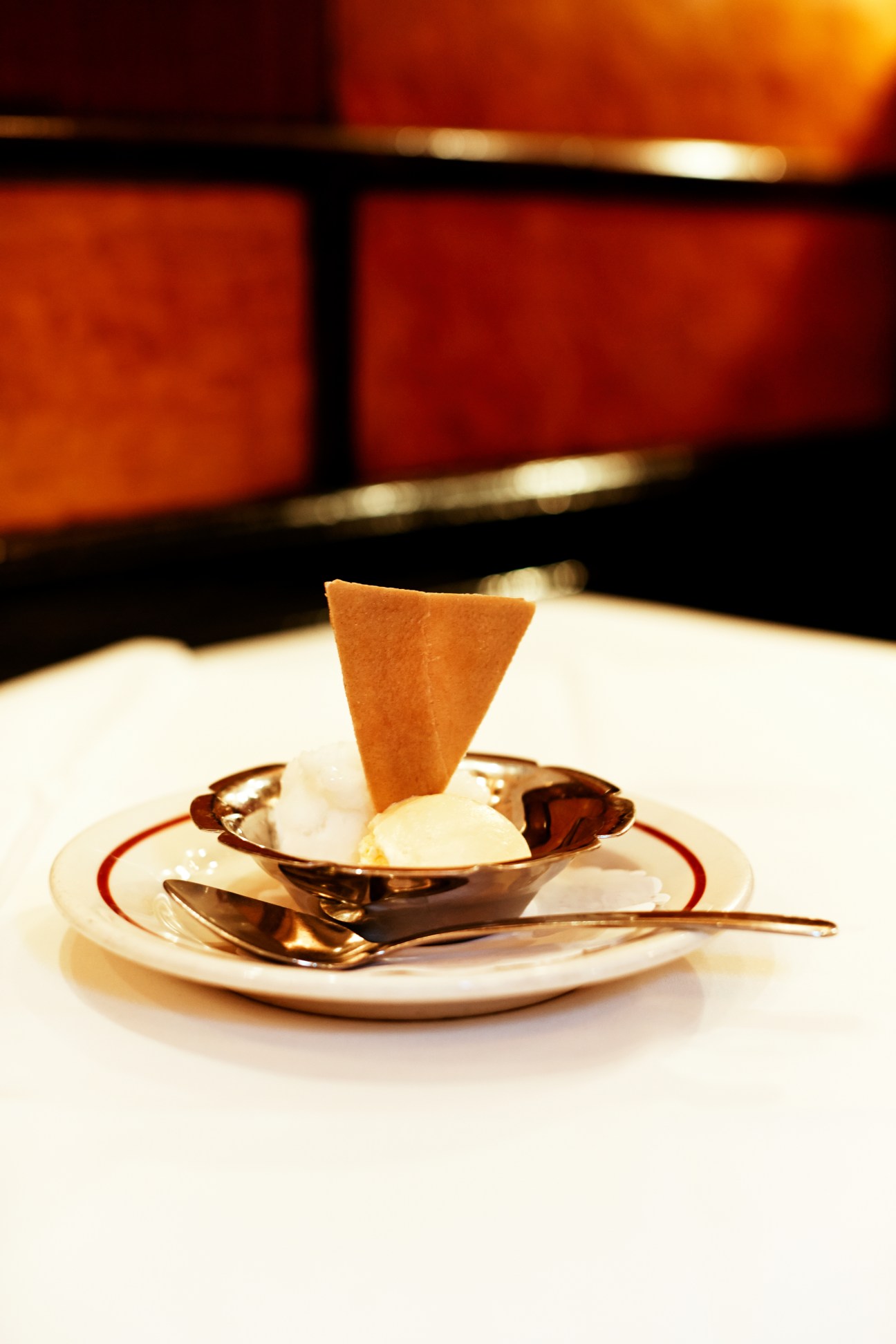Lemon sorbet served in a bowl with a crispy tuile cookie, set on a white plate with red trim at Le Veau d'Or.