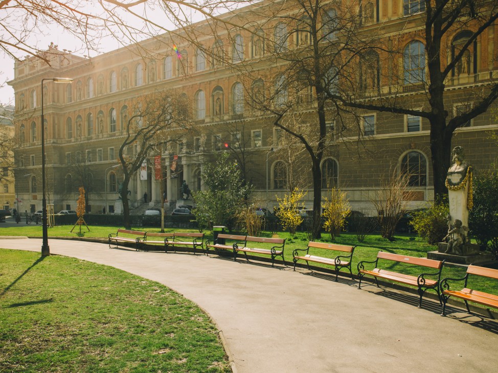 Vienna's Academy of Fine Arts main building on Schillerplatz with benches in foreground and bare trees.