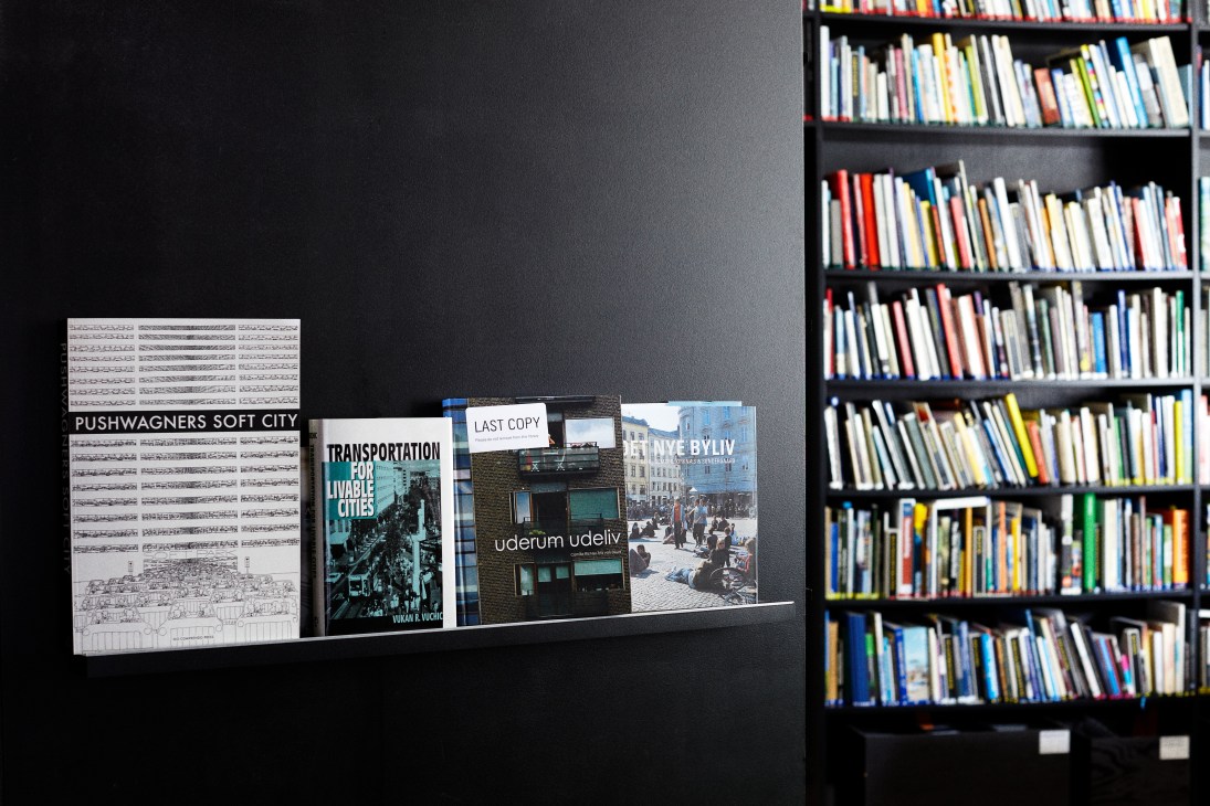 Books and architectural publications displayed on a black shelf in Gehl Architects' reception area.