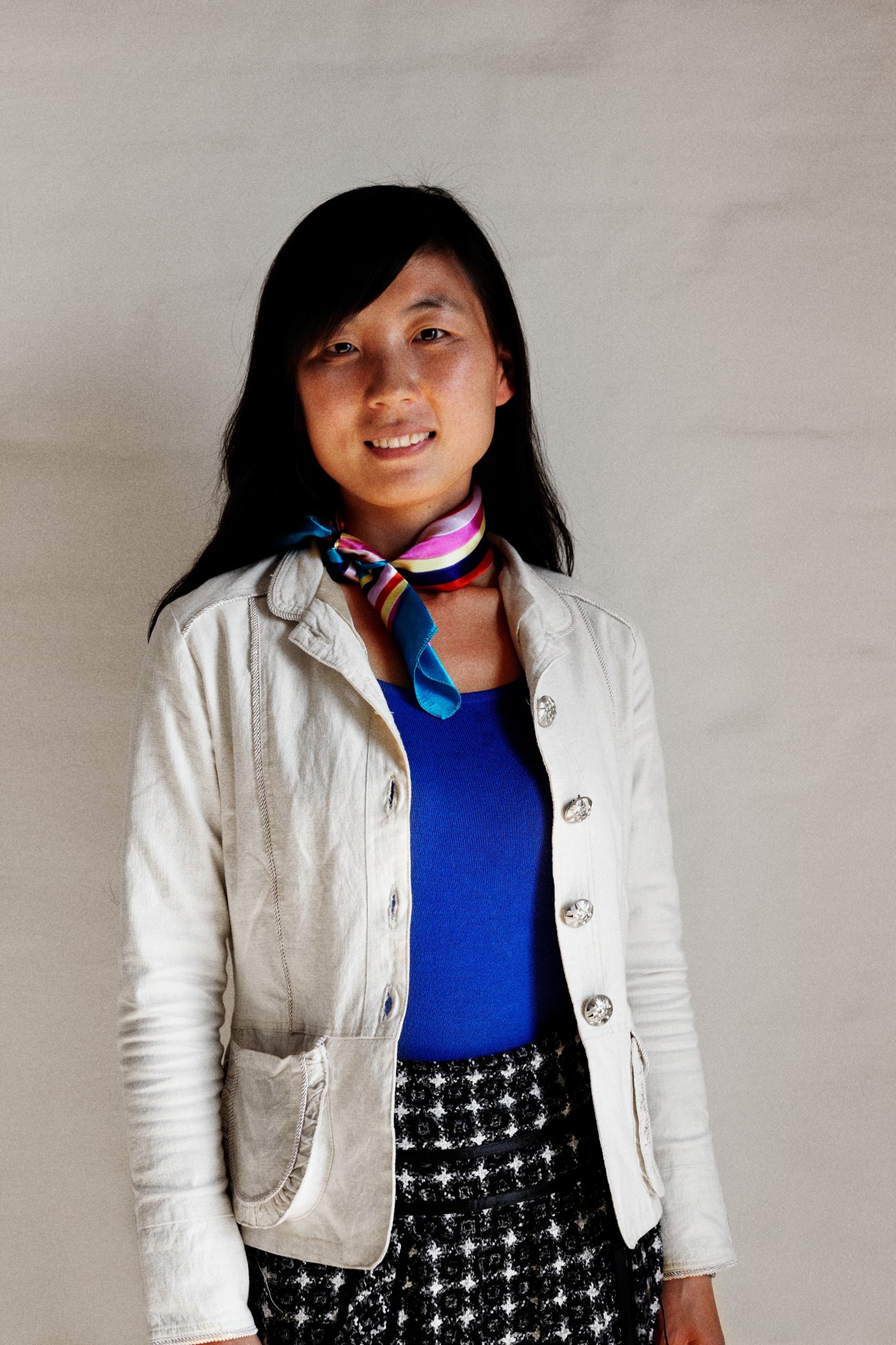 Chunli Zhao, an MA urban planning student from Harbin, China, smiles at the camera wearing a white blazer and colorful scarf.