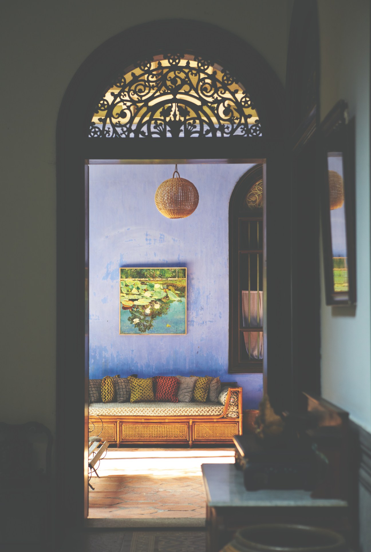 Interior of Cheong Fatt Tze's Blue Mansion with ornate lattice work, hanging globe light, and decorative bench with patterned cushions.