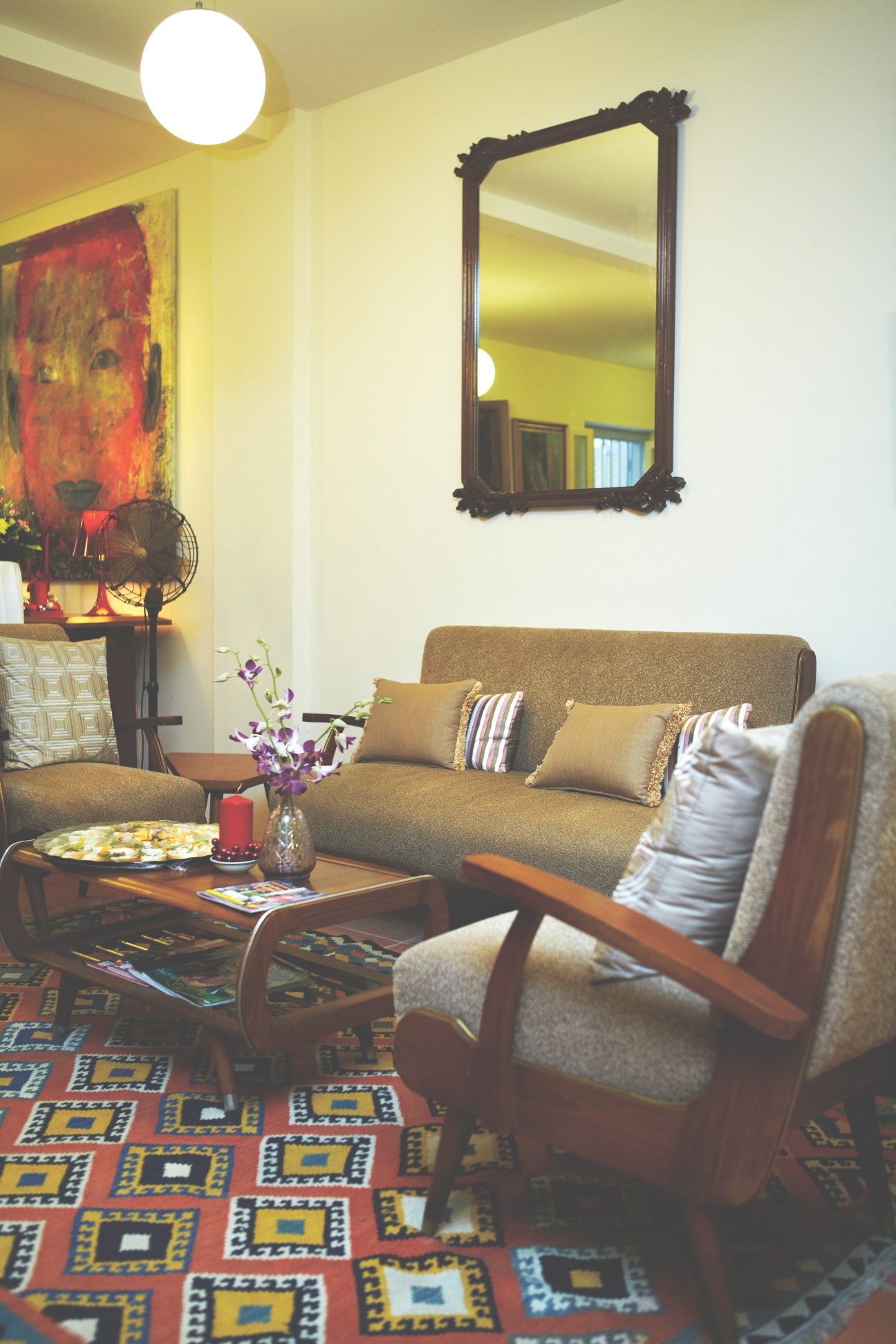 Interior of La Bohéme café with tan sofa, wooden chair, decorative mirror, and patterned rug.