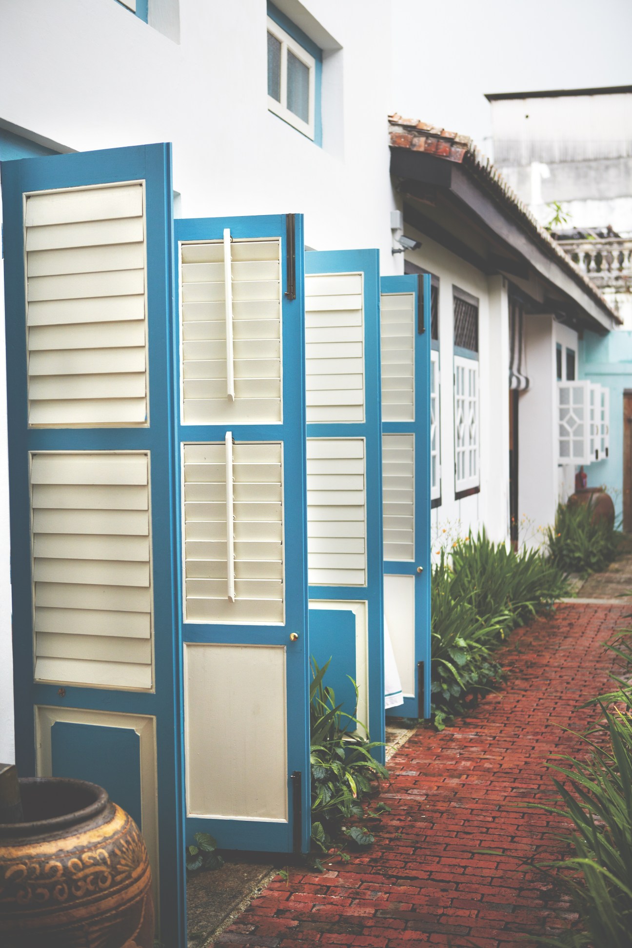 Blue wooden shuttered doors and white walls line a brick pathway in Rebecca Duckett's house on China Street in George Town.