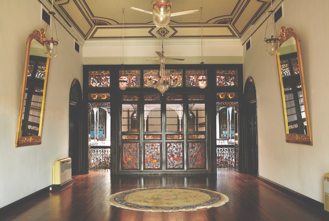 Interior hallway with ornate black carved doors, gold-framed mirrors, and decorative ceiling panels.