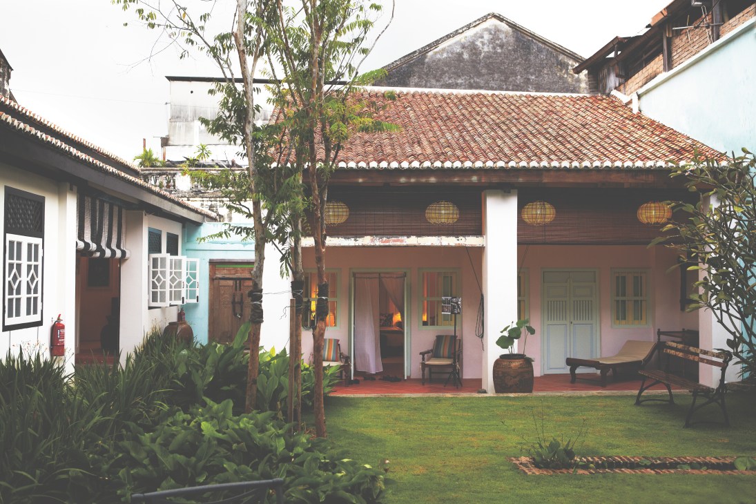 Courtyard of Lovelane boutique hotel with traditional architecture and lush greenery.