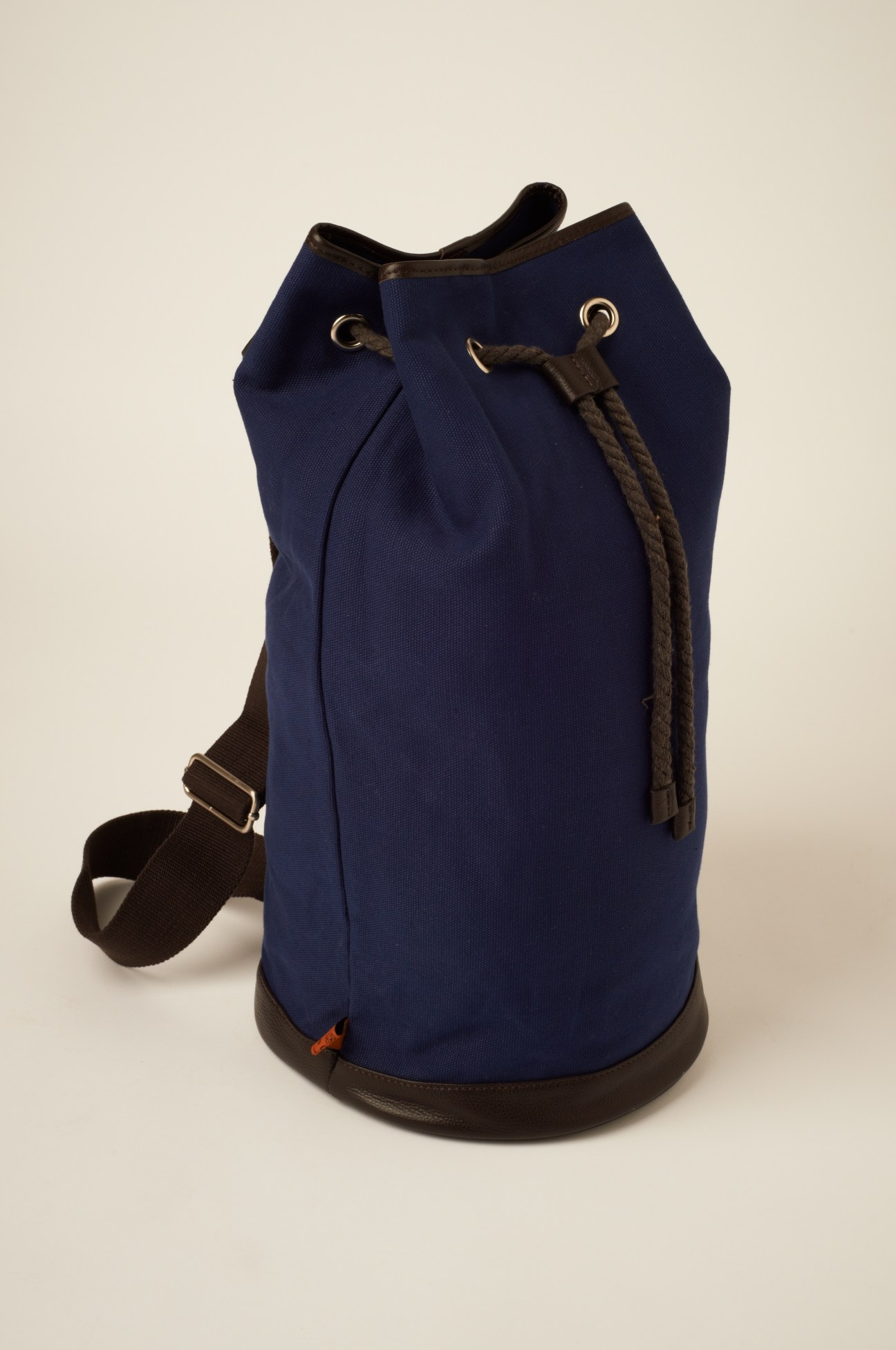Navy canvas duffle bag with brown leather base and drawstring closure by Simon Carter.