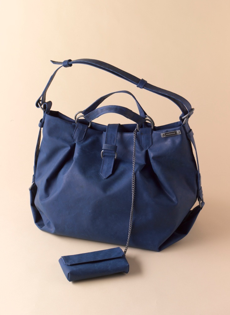 Navy blue Freitag tote bag with rope handles and detachable pouch on beige background.
