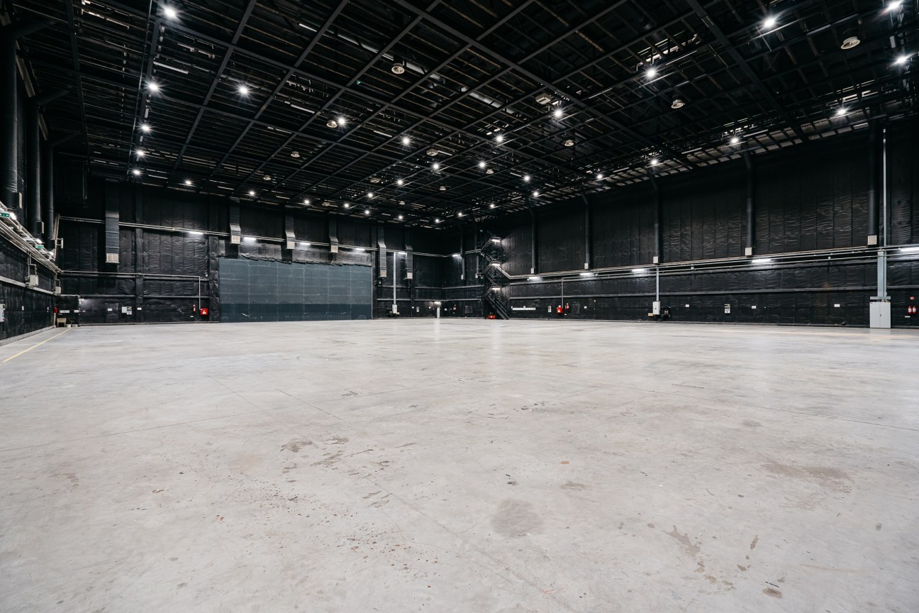 Empty soundstage at Origo Studios with concrete floor and industrial lighting rig overhead.
