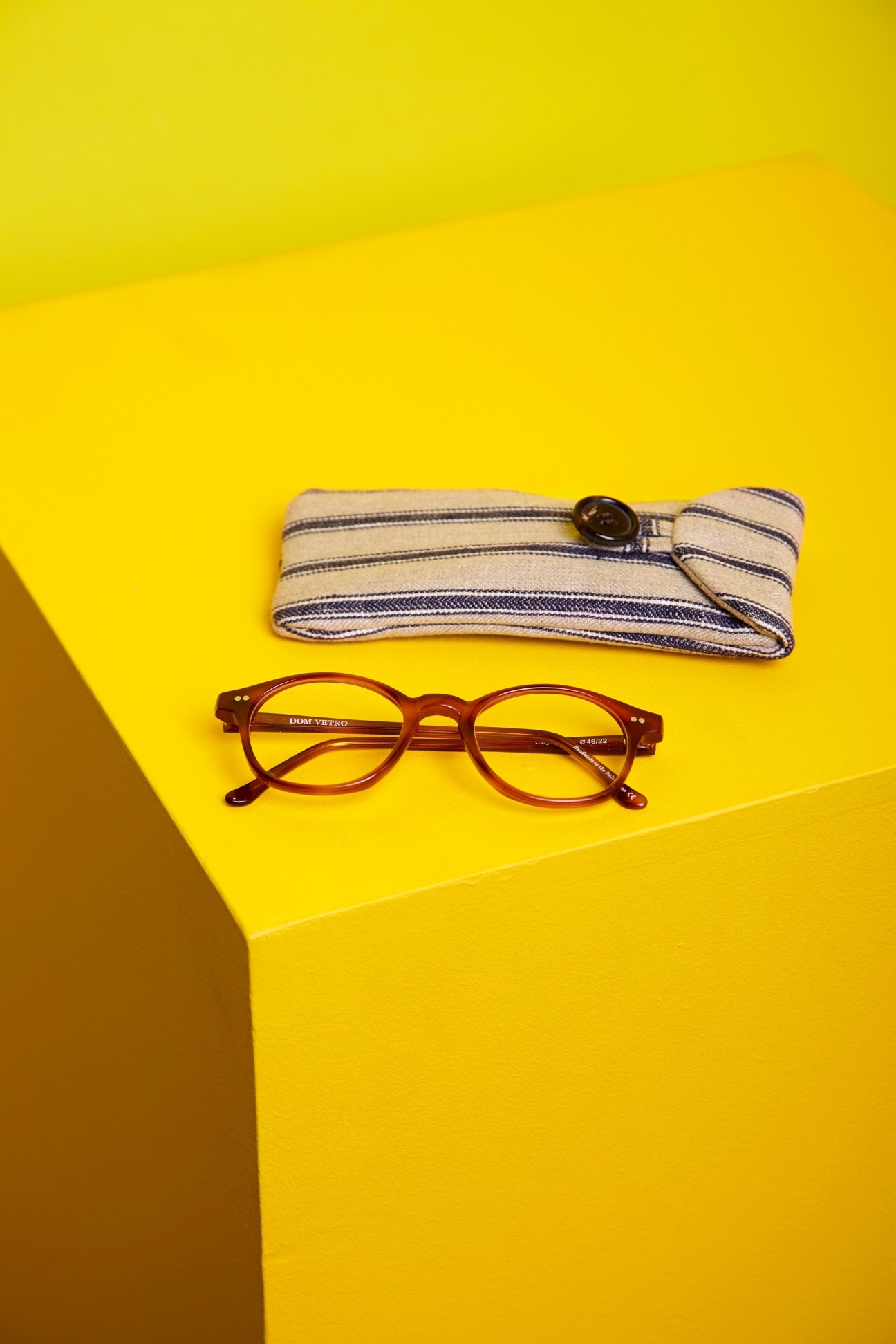 Dom Vetro Capretta spectacles in tortoiseshell acetate with striped fabric case on yellow background.