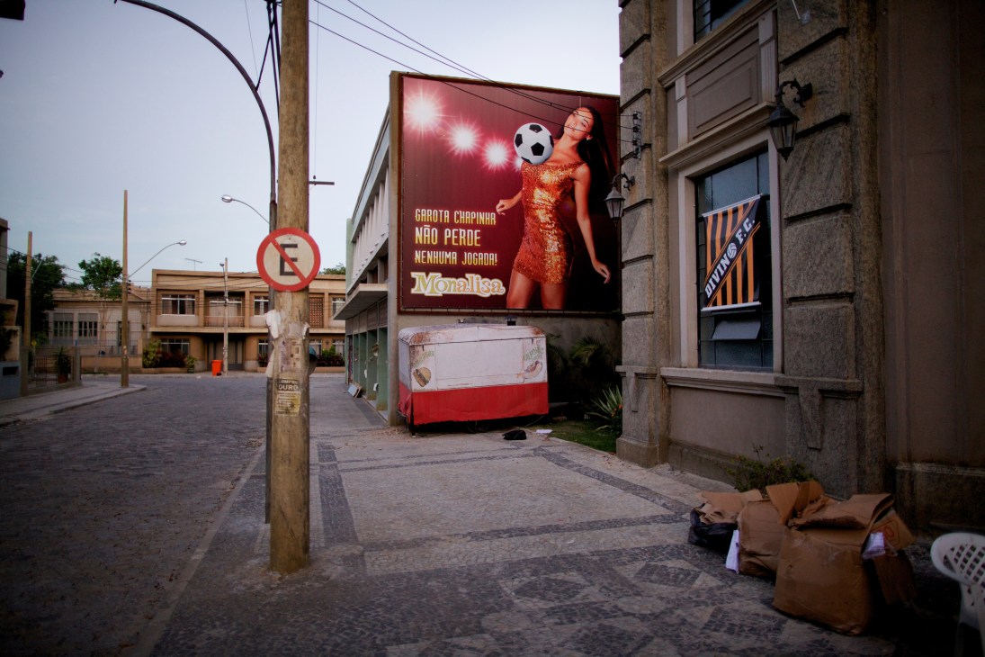 Billboard advertisement for Monalisa beer featuring woman in red dress with soccer ball on urban street set.