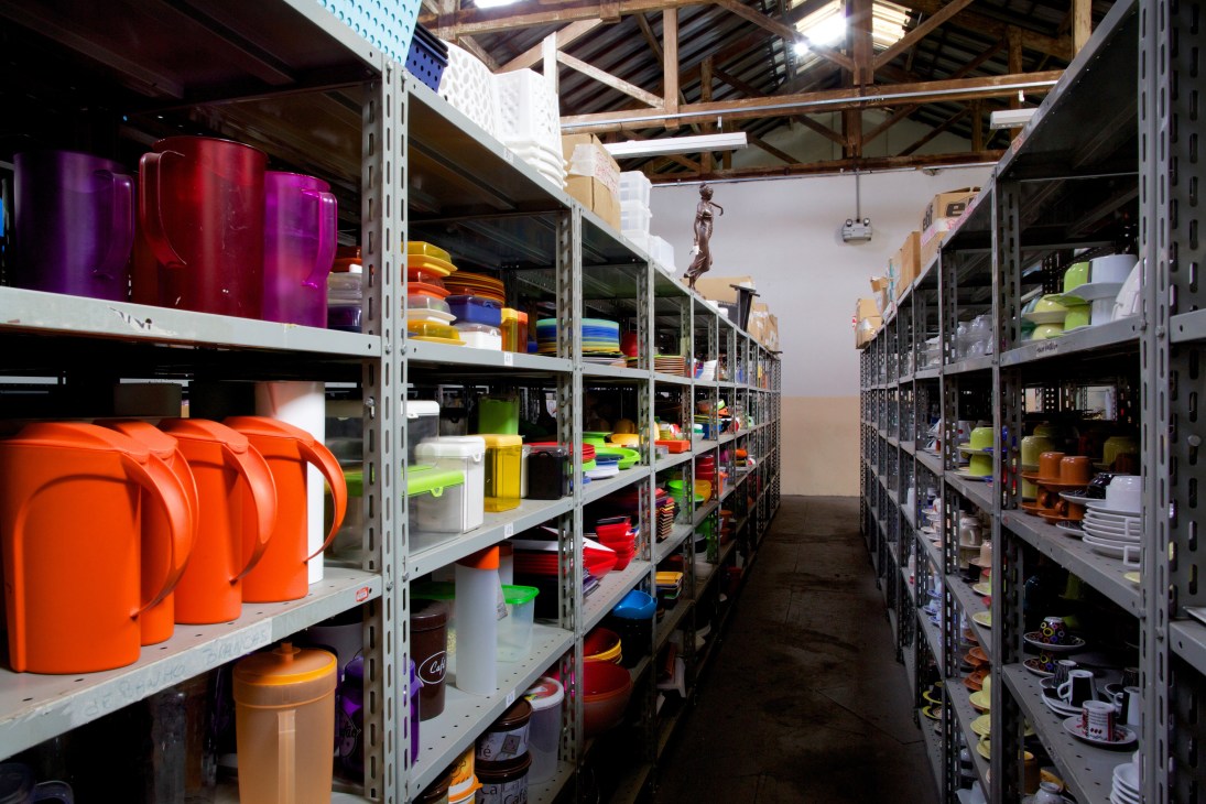 Record's prop department warehouse with shelves of colorful plastic containers and production equipment.