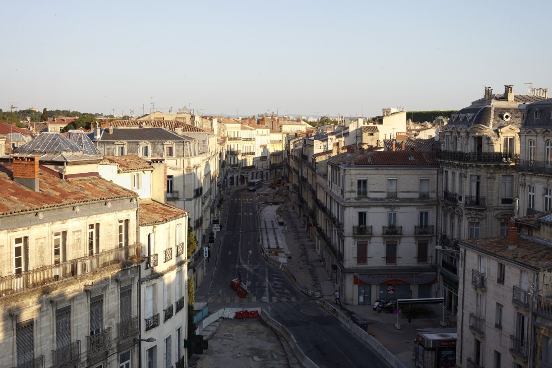 Aerial view of Montpellier's old town centre with sandstone buildings, iron balconies, and narrow streets.